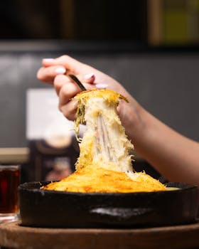 A delicious close-up of a cheesy baked dish being served from a cast iron skillet.