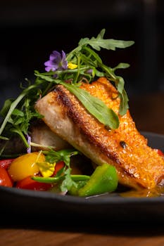 Delicious grilled salmon served with fresh vegetables, herbs, and vibrant flowers.